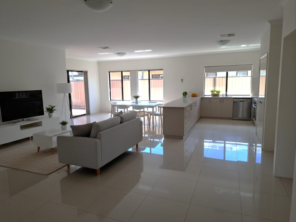 Spacious open-plan living, dining and kitchen area with large floor tiles, plenty of windows and a door to outside
